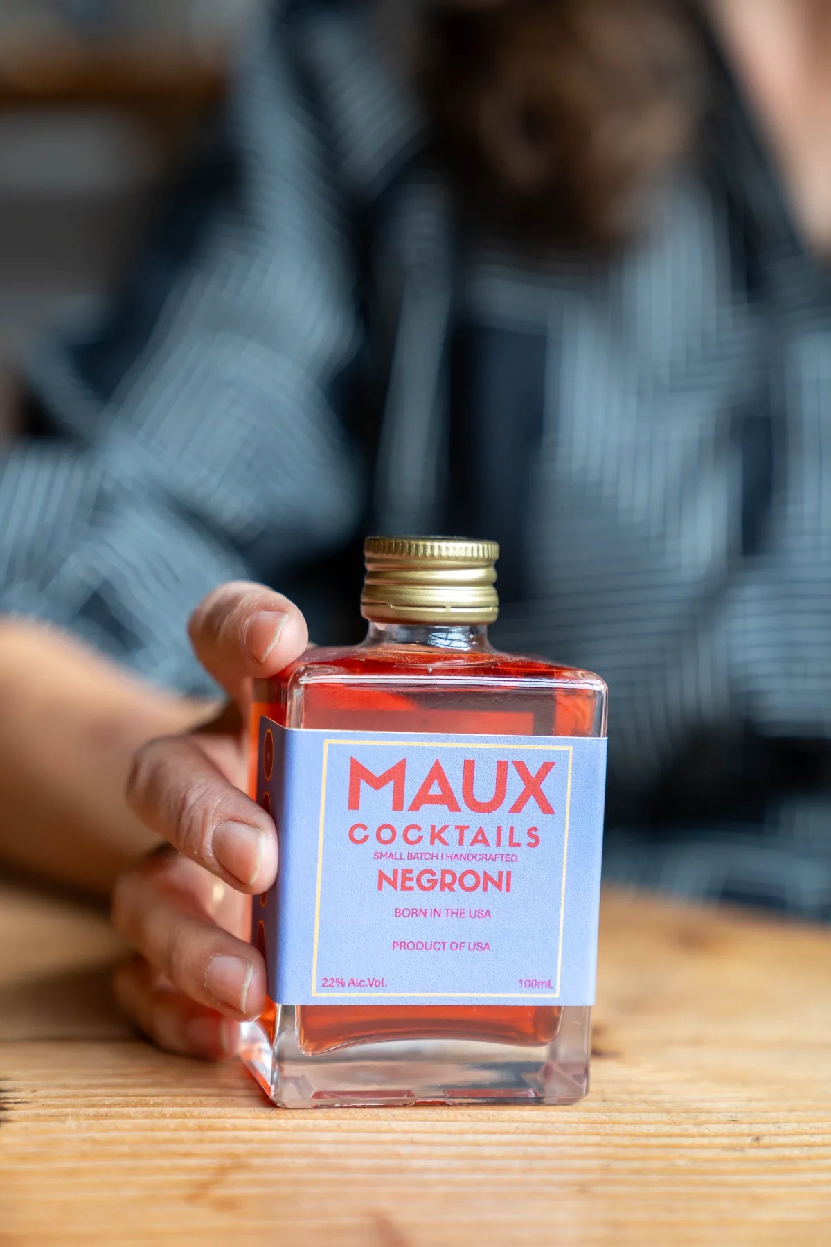 A guest holding a Maux Negroni at the table